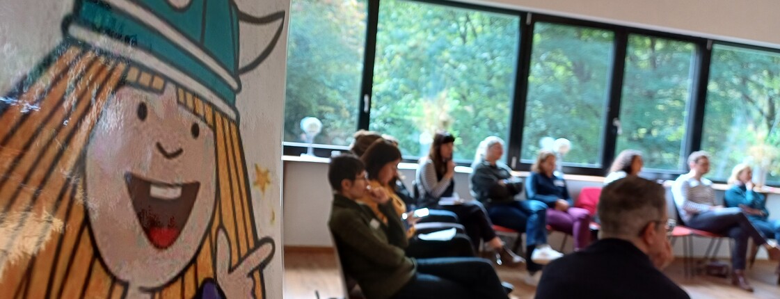 Teilnehmer*innen eines Workshops sitzen im Sesselkreis und denken nach