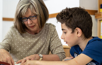 Ehrenamtliche erklärt einem Schüler den Lernstoff im direkten Gespräch am Tisch